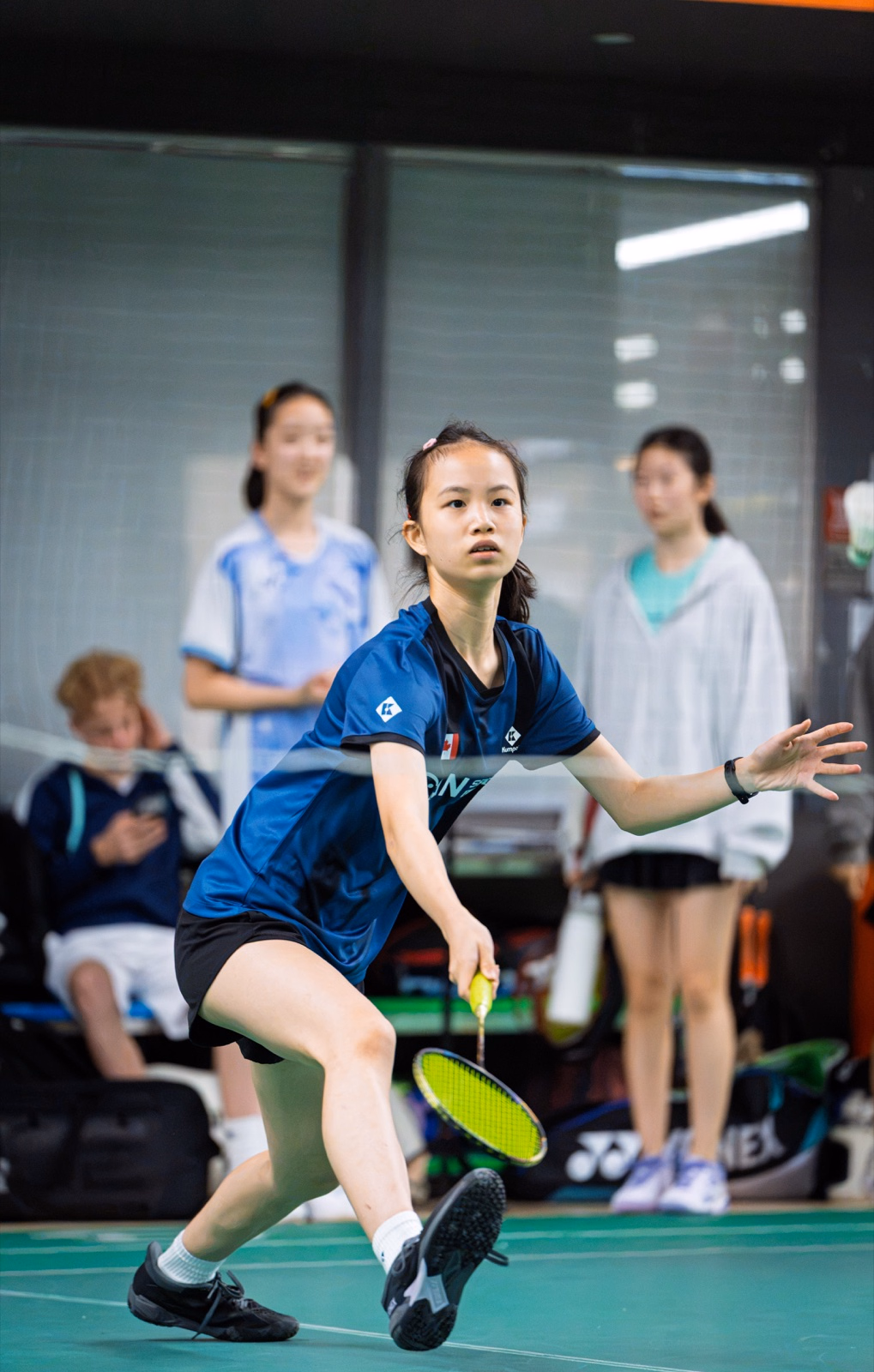 Badminton Ontario player in blue lunging low across the court for a return