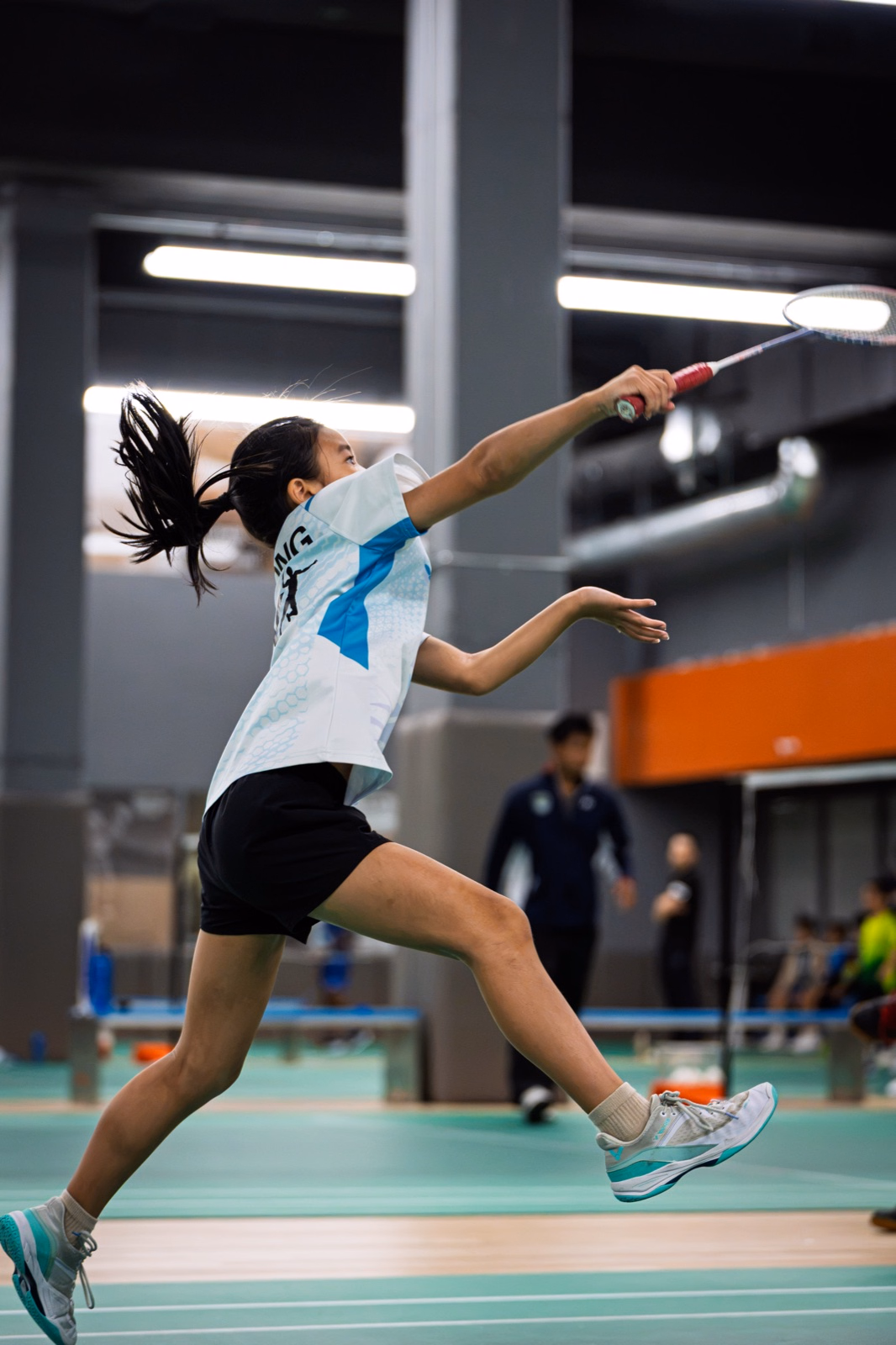 Badminton Ontario player airborne and stretching across the court for an overhead return
