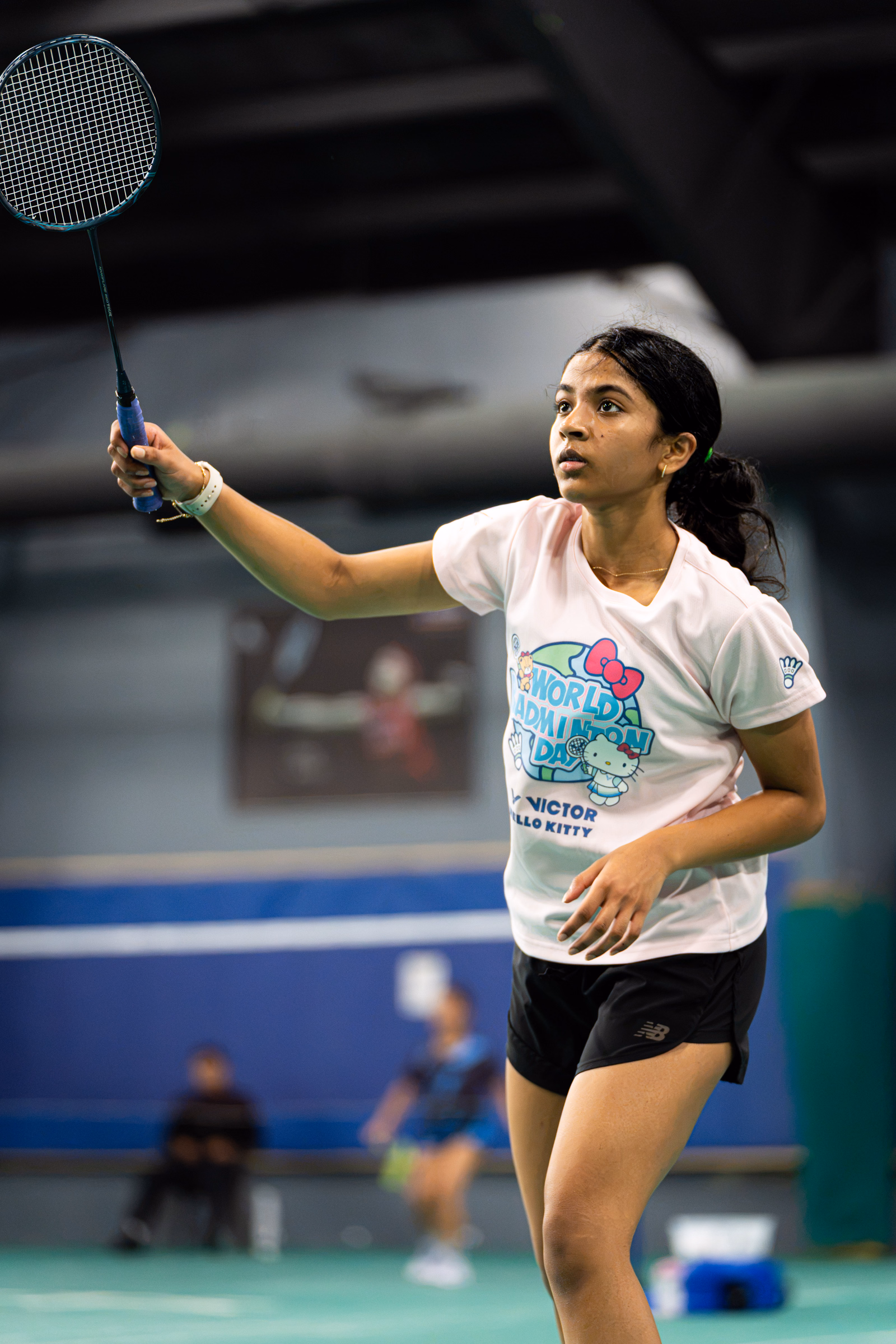 Badminton player tracking the shuttlecock with her racket raised